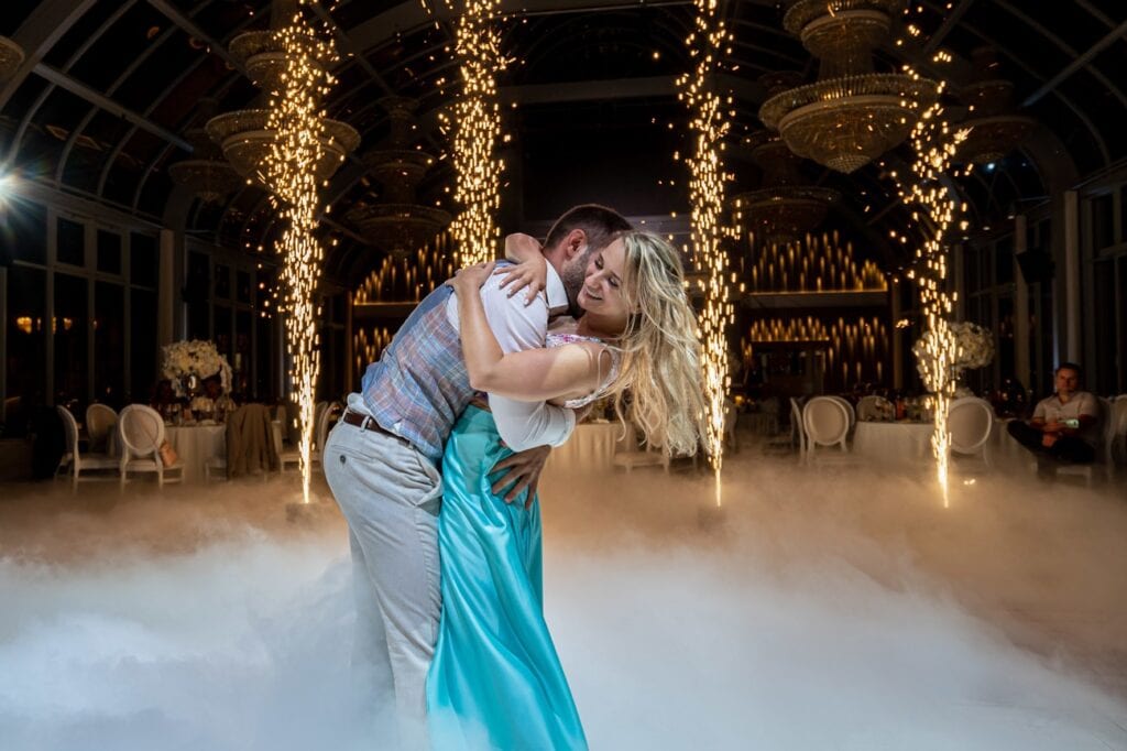 Trockeneis für hochzeiten – spektakulärer eröffnungstanz & tanzen auf wolken „nebelmaschine“-effekt 4 Ein Paar tanzt auf einer Hochzeit mit Feuerwerk, Rauch, runden Tischen, Blumendekorationen.
